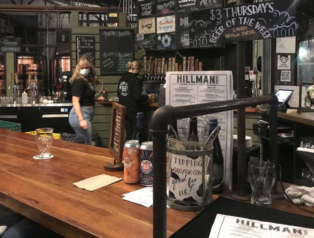 the bar, taps and beer list at Hillman Beer, with two staff in the background