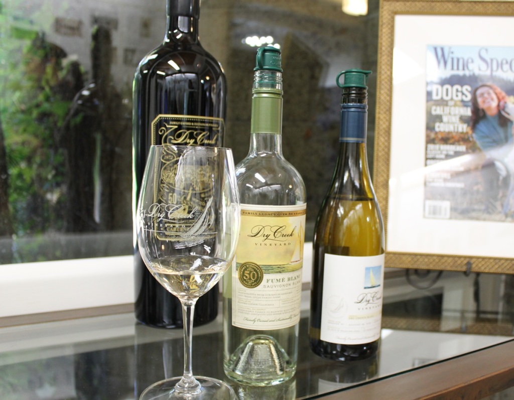three bottles of wine on a table, with a glass in the foreground