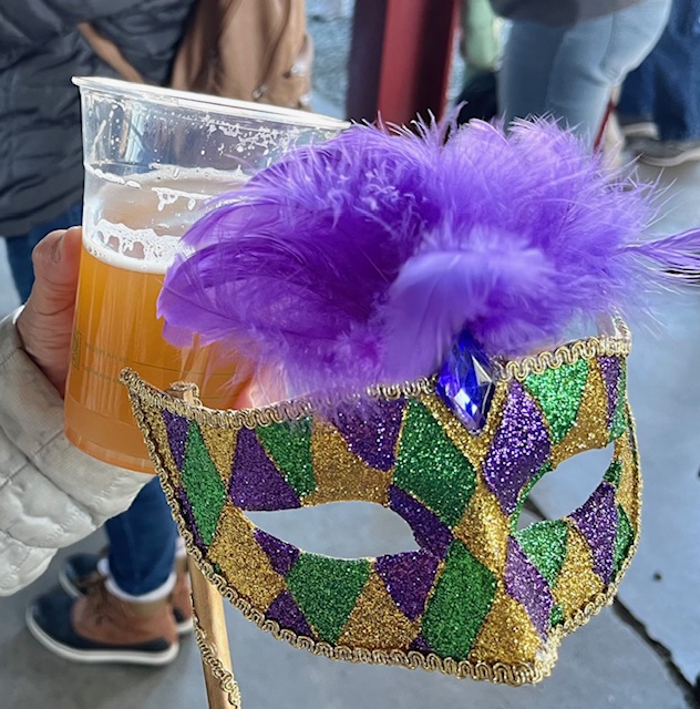 Mardi Gras mask with a beer in the background